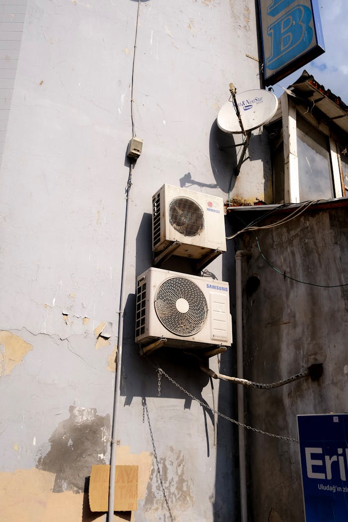 Vertical shot of rusty air conditioners on an urban building facade, showing wear and decay.