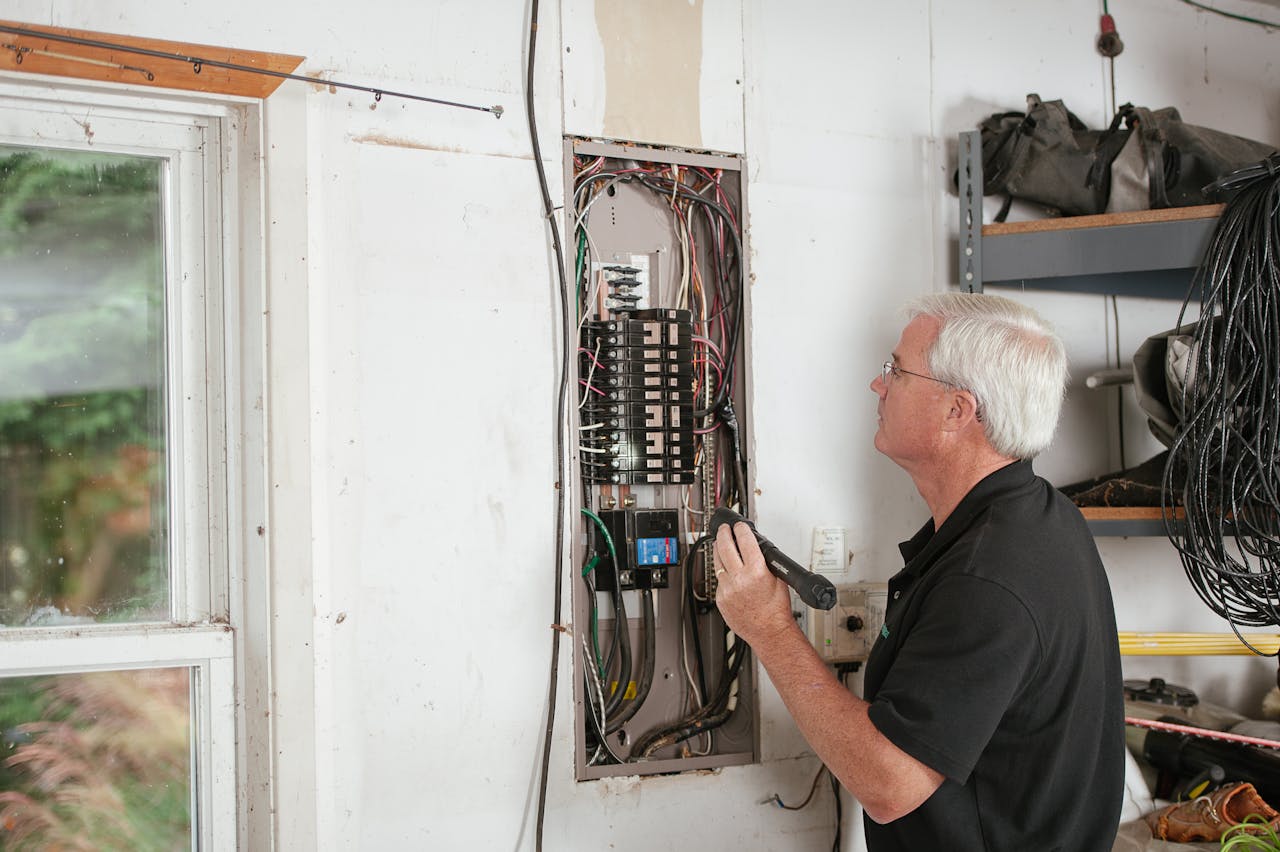 An electrician carefully examines a residential fuse box indoors, ensuring electrical safety and compliance.